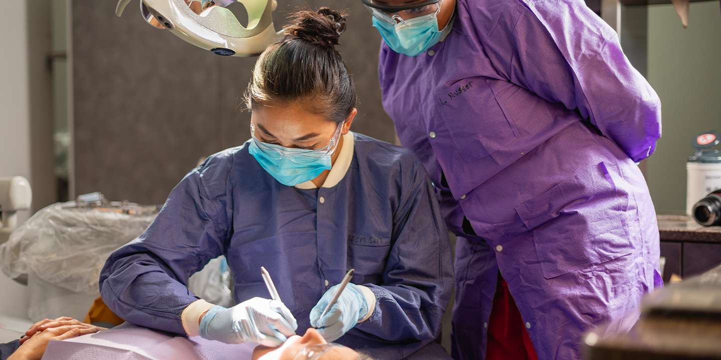 Dental instructor and student working on client