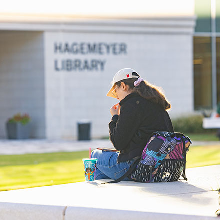 student siting outside with backpack in from of Hagemeyer Library at Central Piedmont 