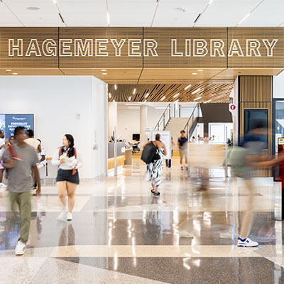 students walking in Parr Center with Hagemeyer Library sign above them