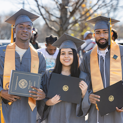 Three Central Piedmont students wearing their caps and gowns at graduation