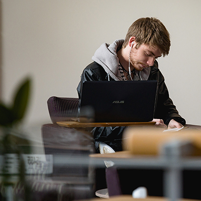 student sitting in front of laptop reading something on the table