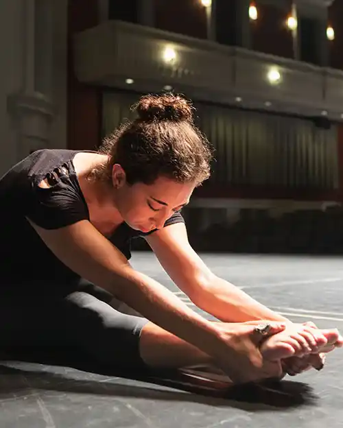 performing arts student sitting on floor of stage of Halton Theater