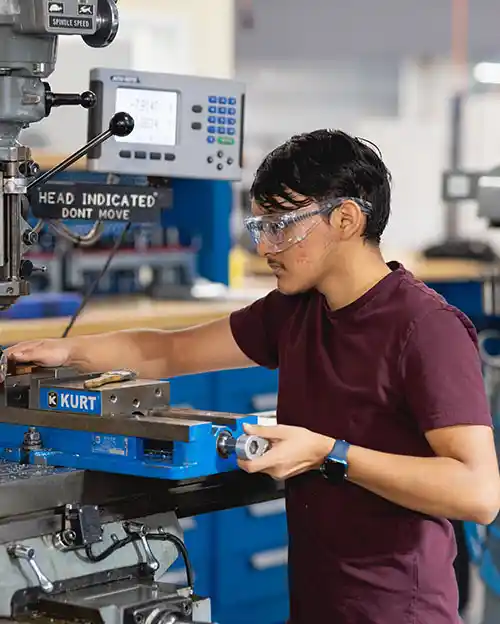 engeering student with safety glasses in front of equipment 