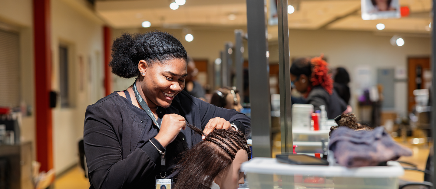 Cosmetology student practicing braiding on a mannequin  