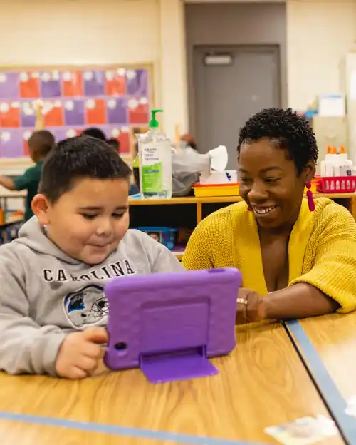 instructor smiling at student looking at tablet inside a classroom at Central Piedmont Community College
