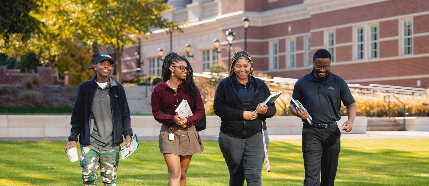 4 students walking across Parr center lawn 