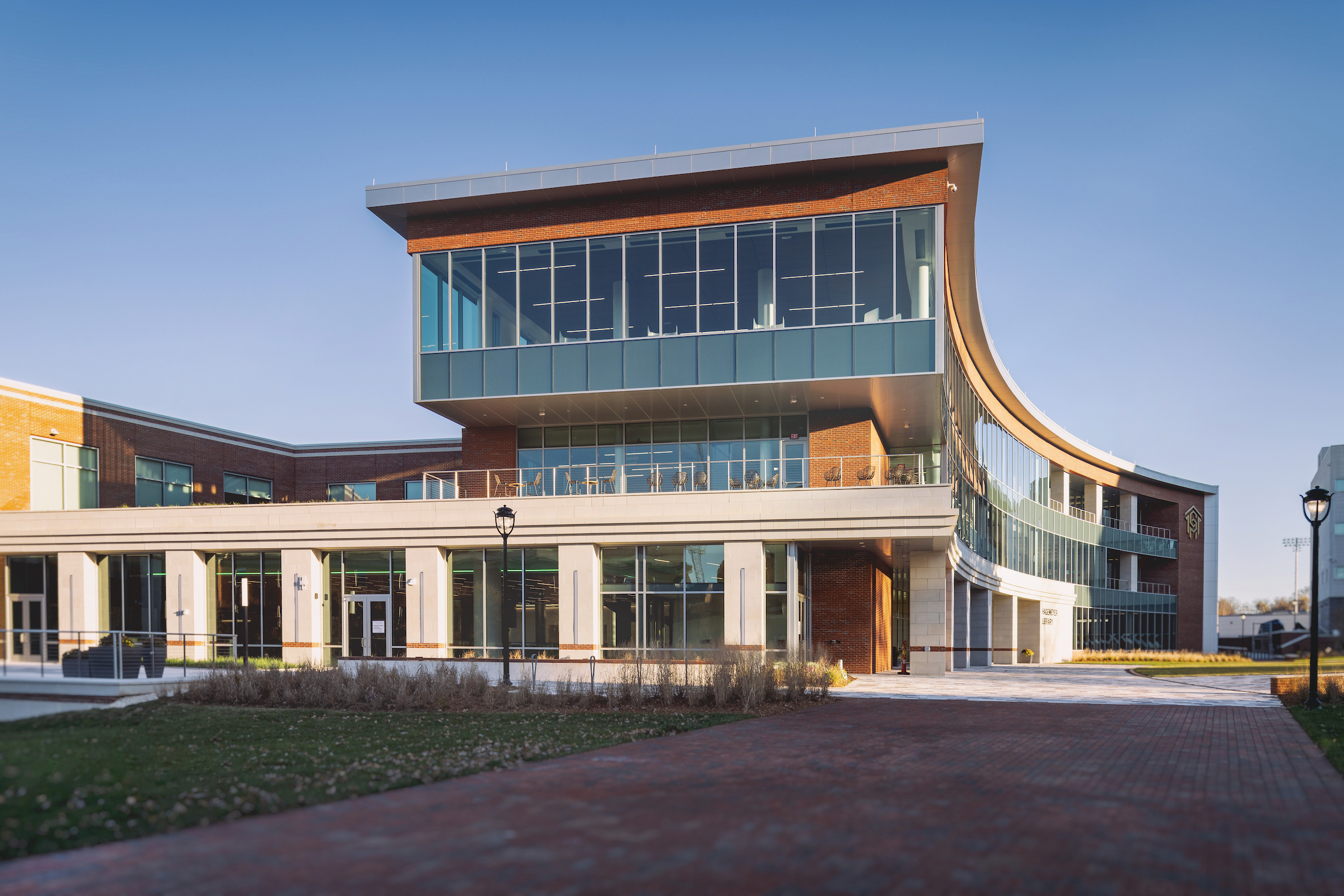 Exterior of large, multistory brick-and-glass Central Campus building with walkways and grass on grounds.