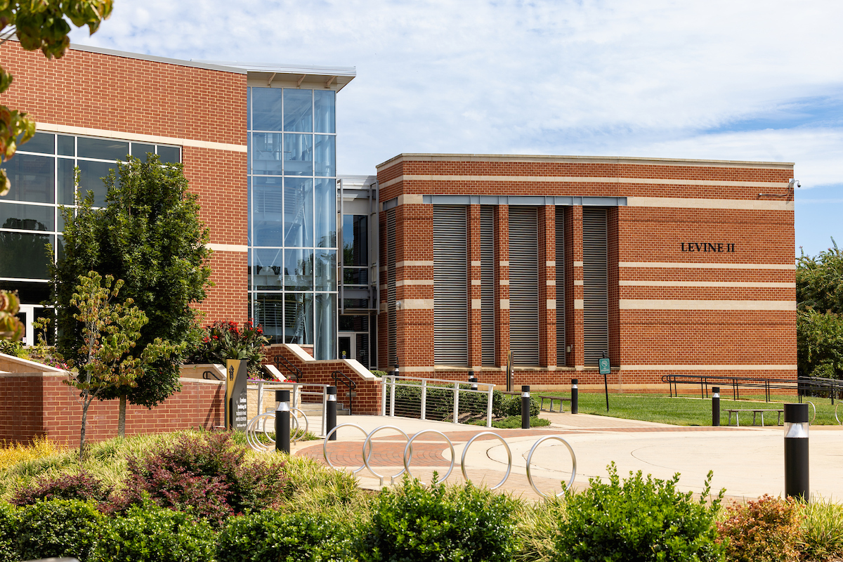 Exterior of large brick Levine Campus building on Central Piedmont’s campus with grounds and walkway in foreground.