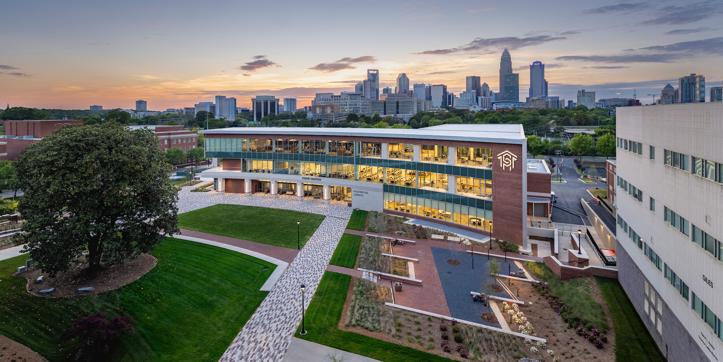 Aerial view of campus buildings with the Charlotte skyline at sunset