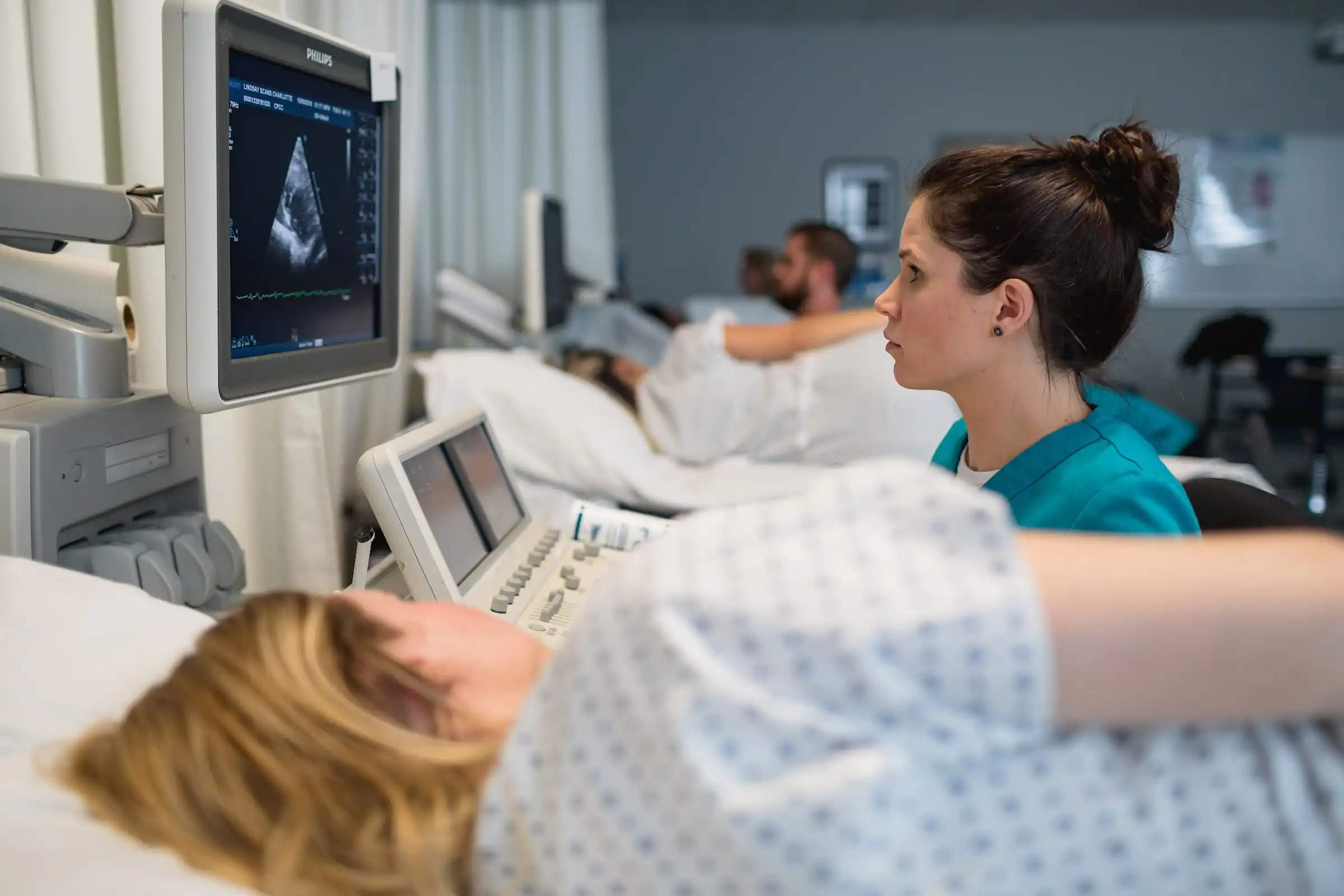 Clinician monitoring an ultrasound scan at a patient's bedside
