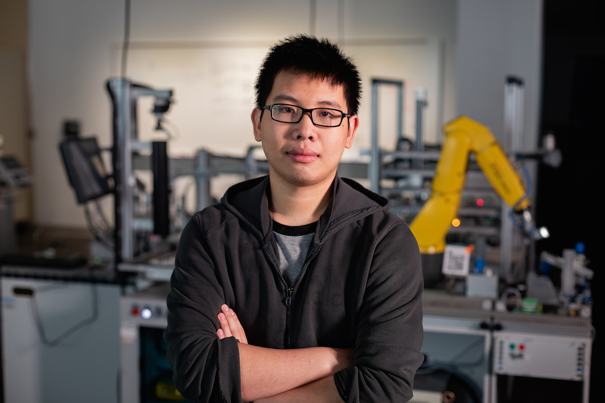 student standing with arms crossed in a mechatronics engineering lab