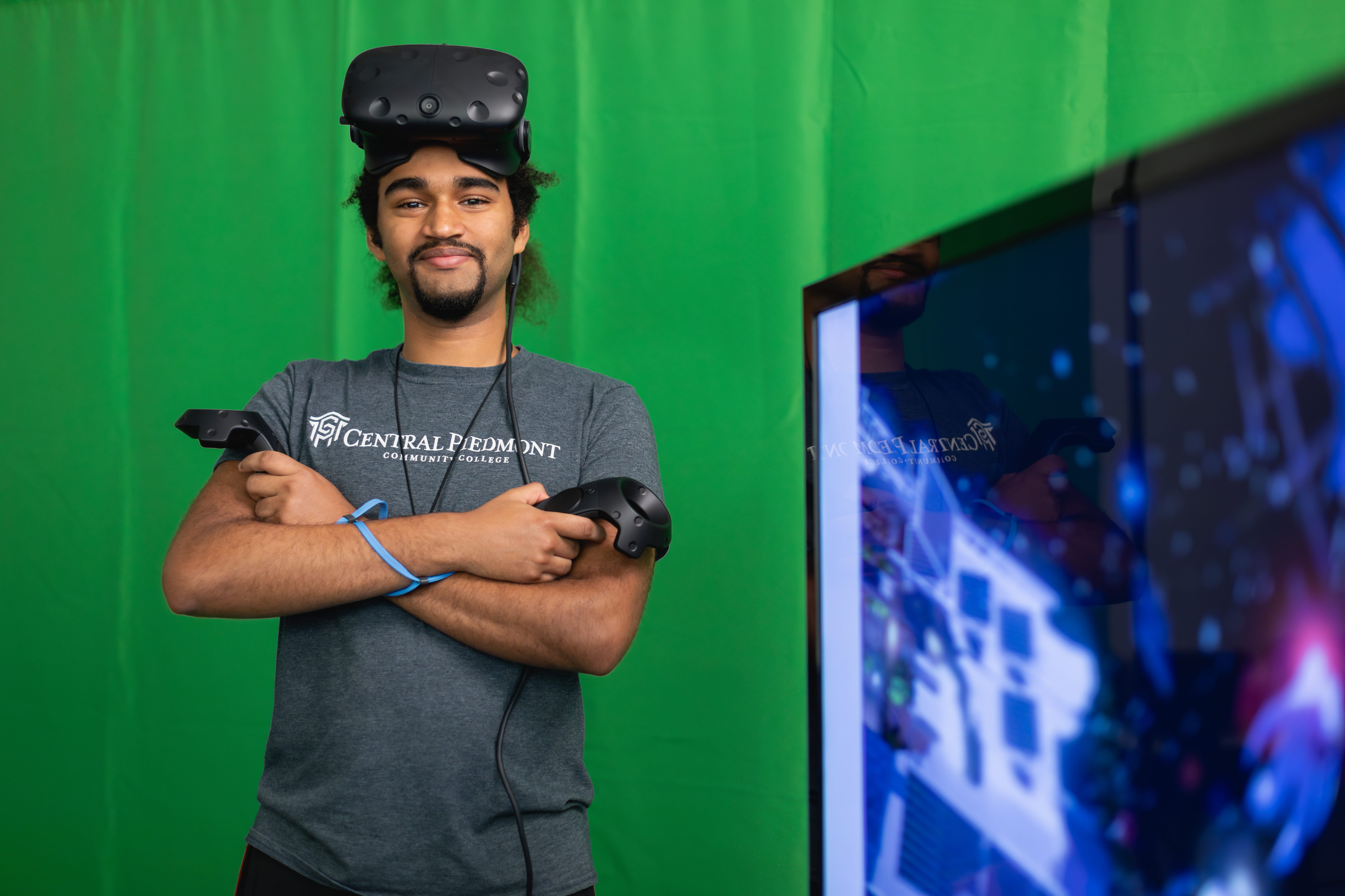 Student wearing a virtual reality headset in front of a green screen