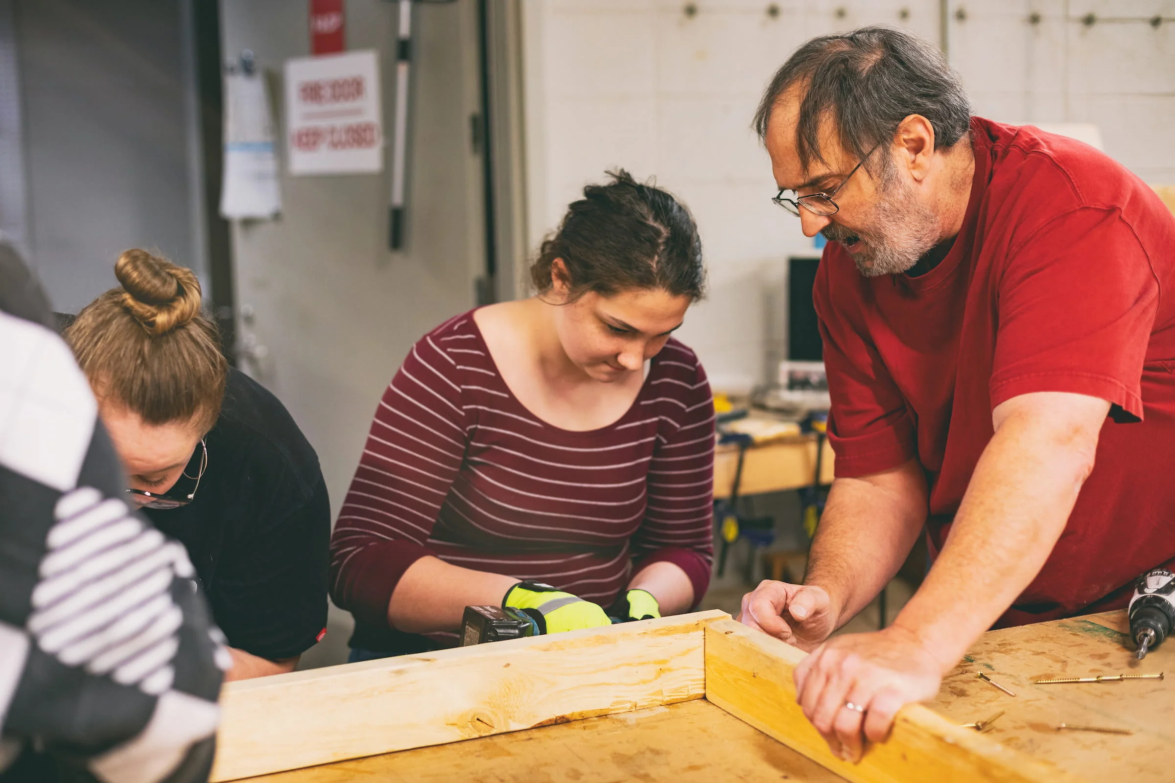 Apprentices measuring and marking timber at a workbench
