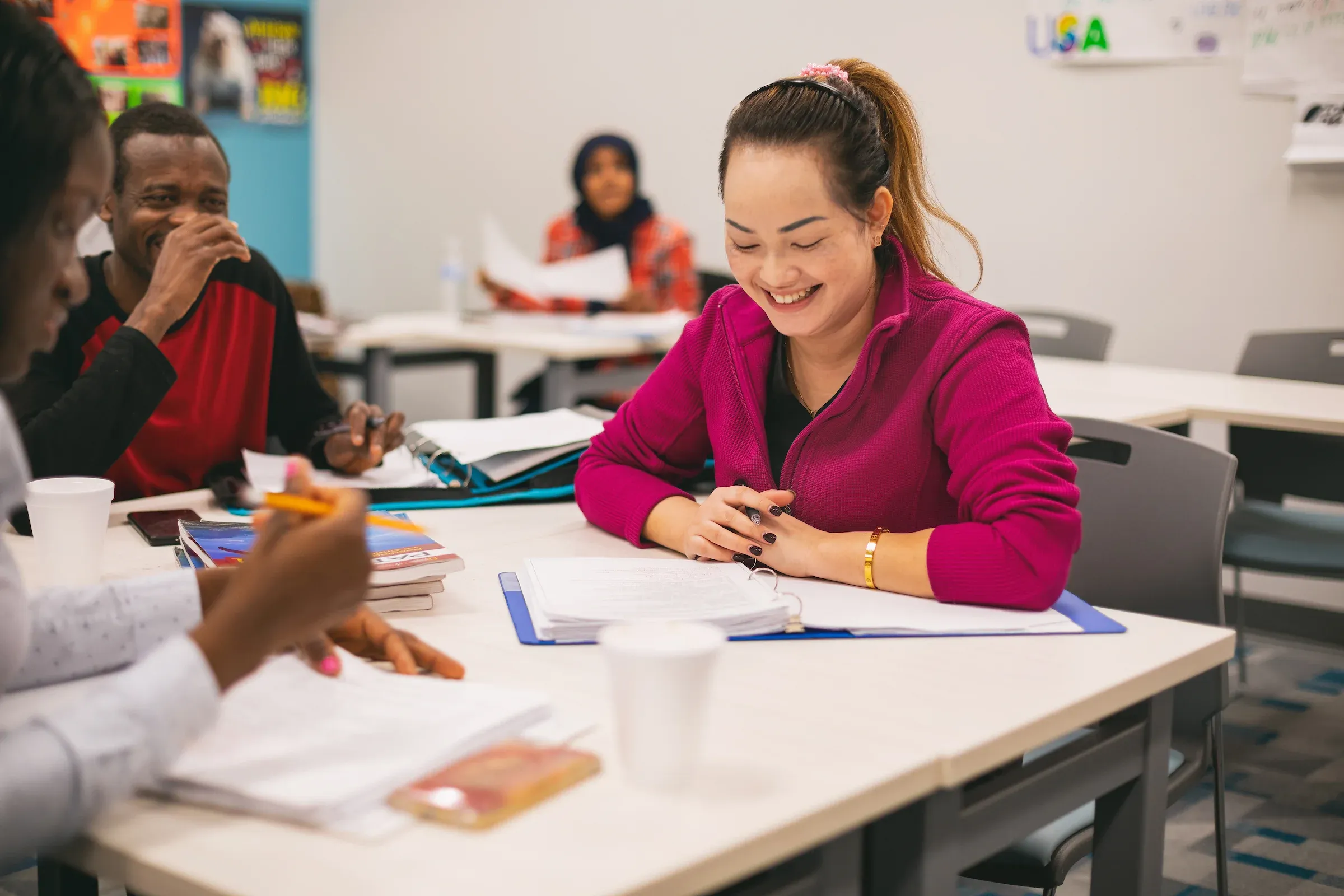 Instructor smiling with students around a classroom table