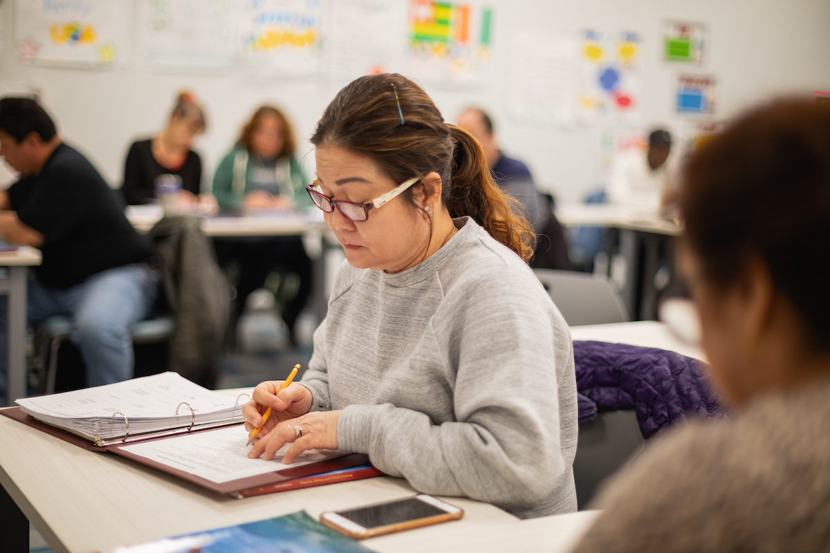 Central Piedmont student looking intently at notes in notebook in campus classroom.