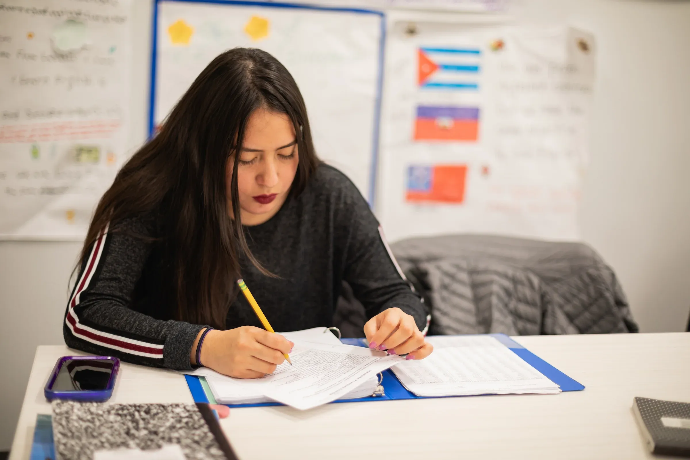 Student completing a placement test at a desk beneath world flags