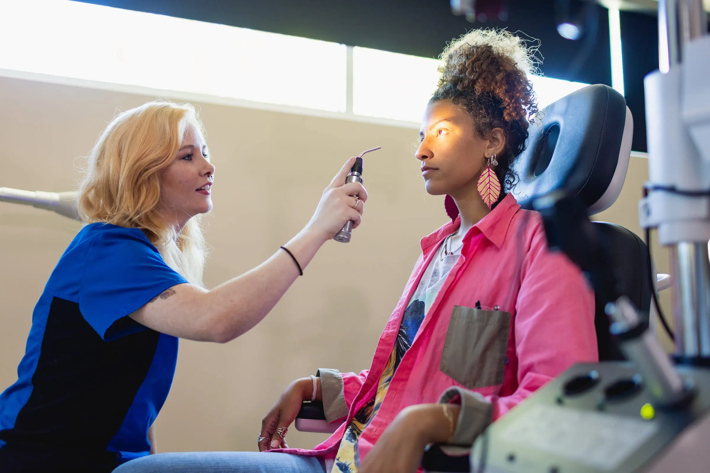 Optometrist examining a patient's eyes with a handheld instrument