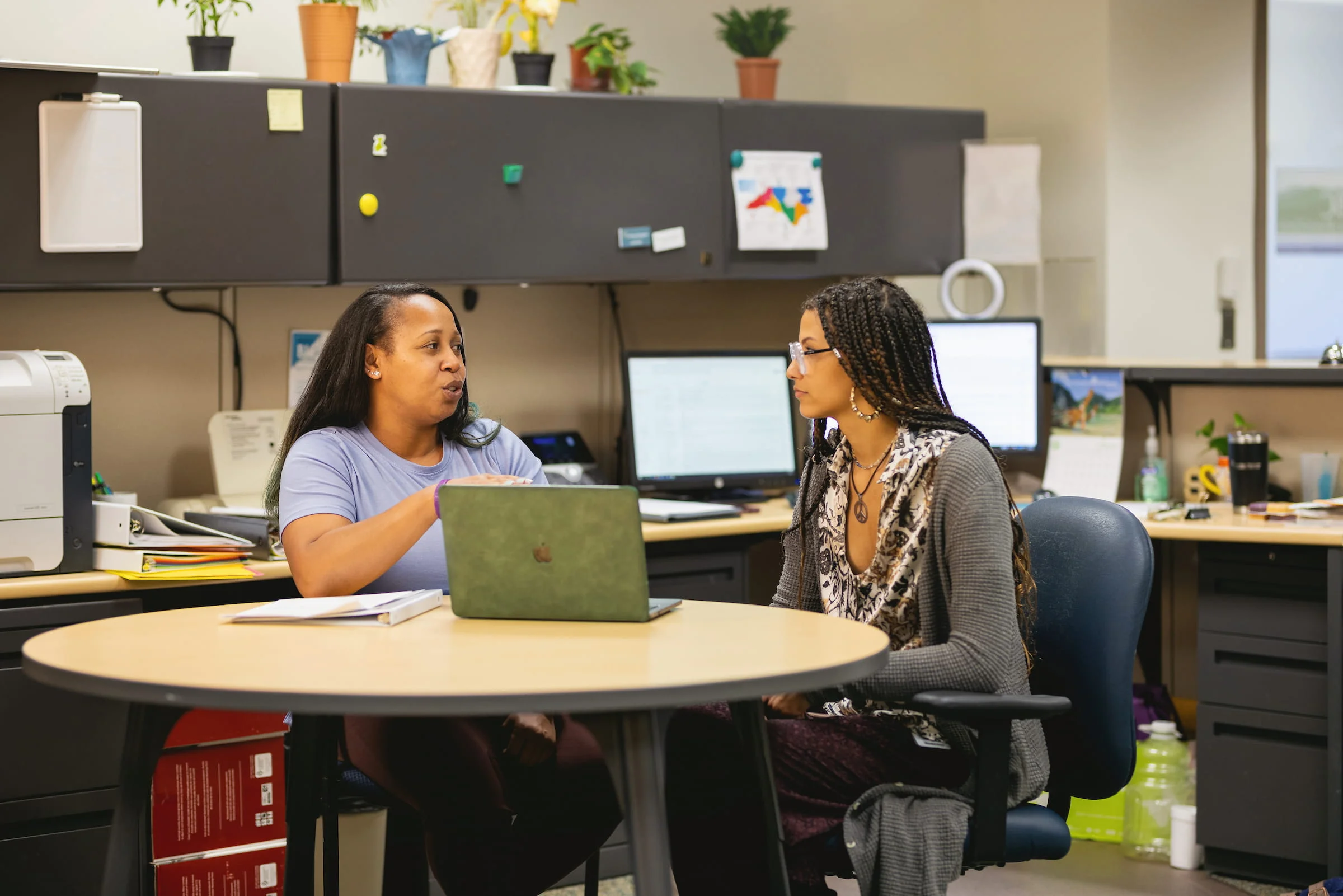 Adviser talking with a student at a table with a laptop