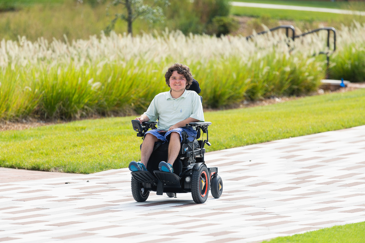 Student riding through the quad in a wheelchair