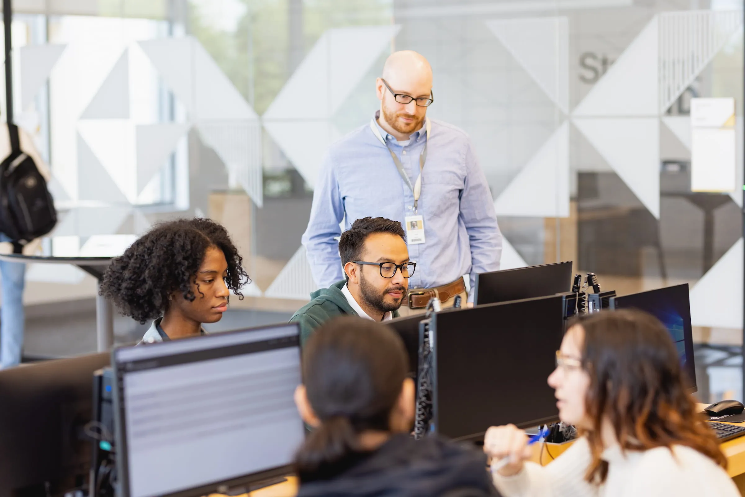 Instructor helping students working at computer workstations