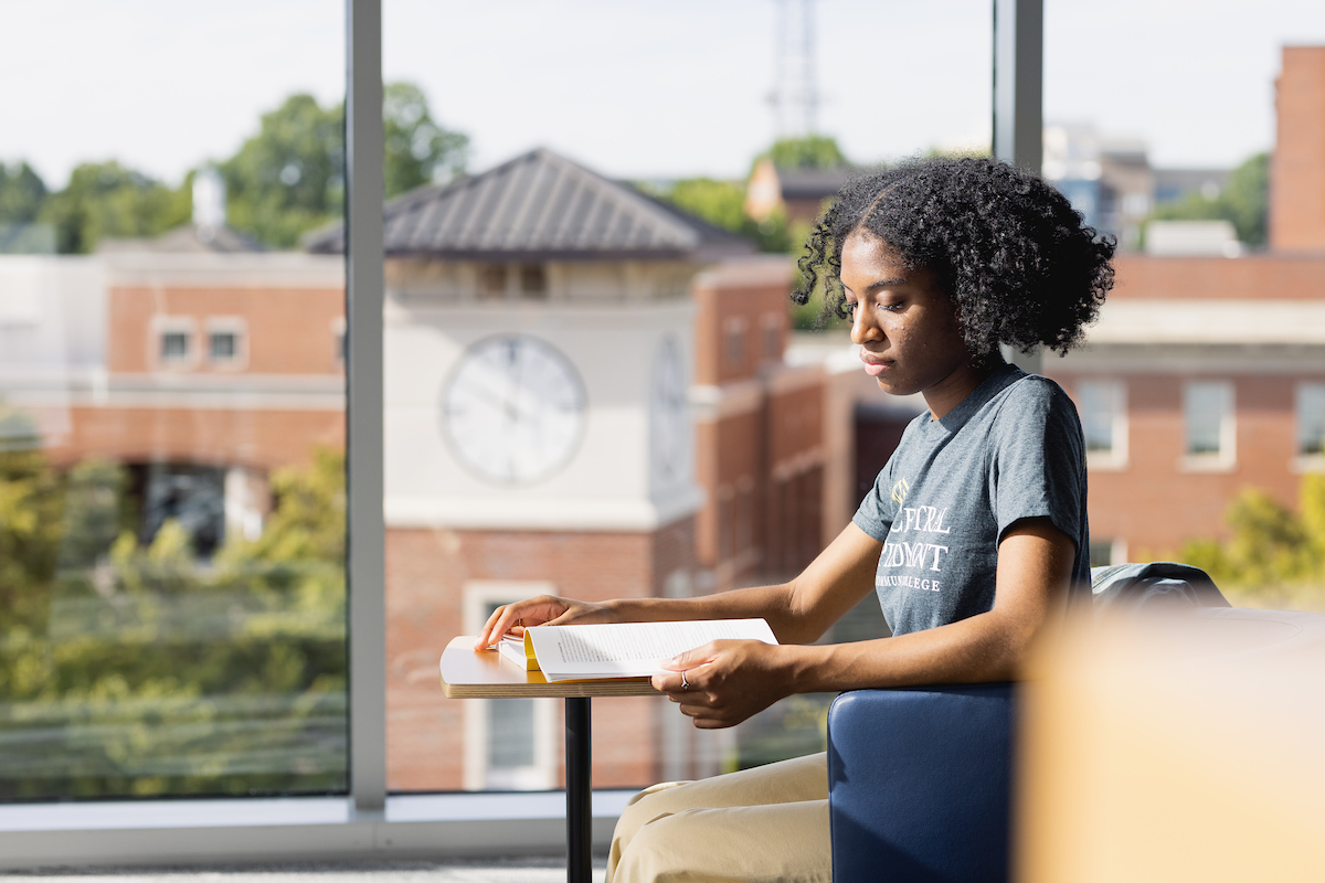 Student studying in the Parr Center with the Central Piedmont clock tower in the background