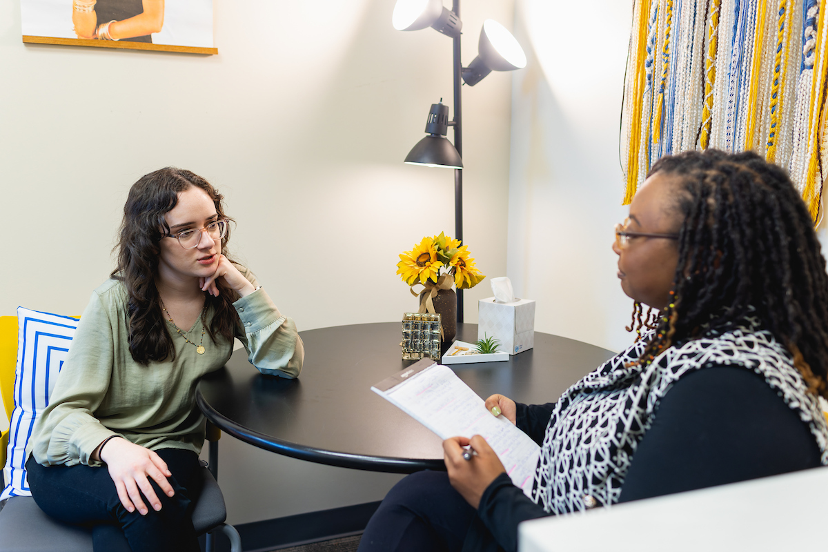 Central Piedmont student chatting with advisor while both sit at small circular table in office.