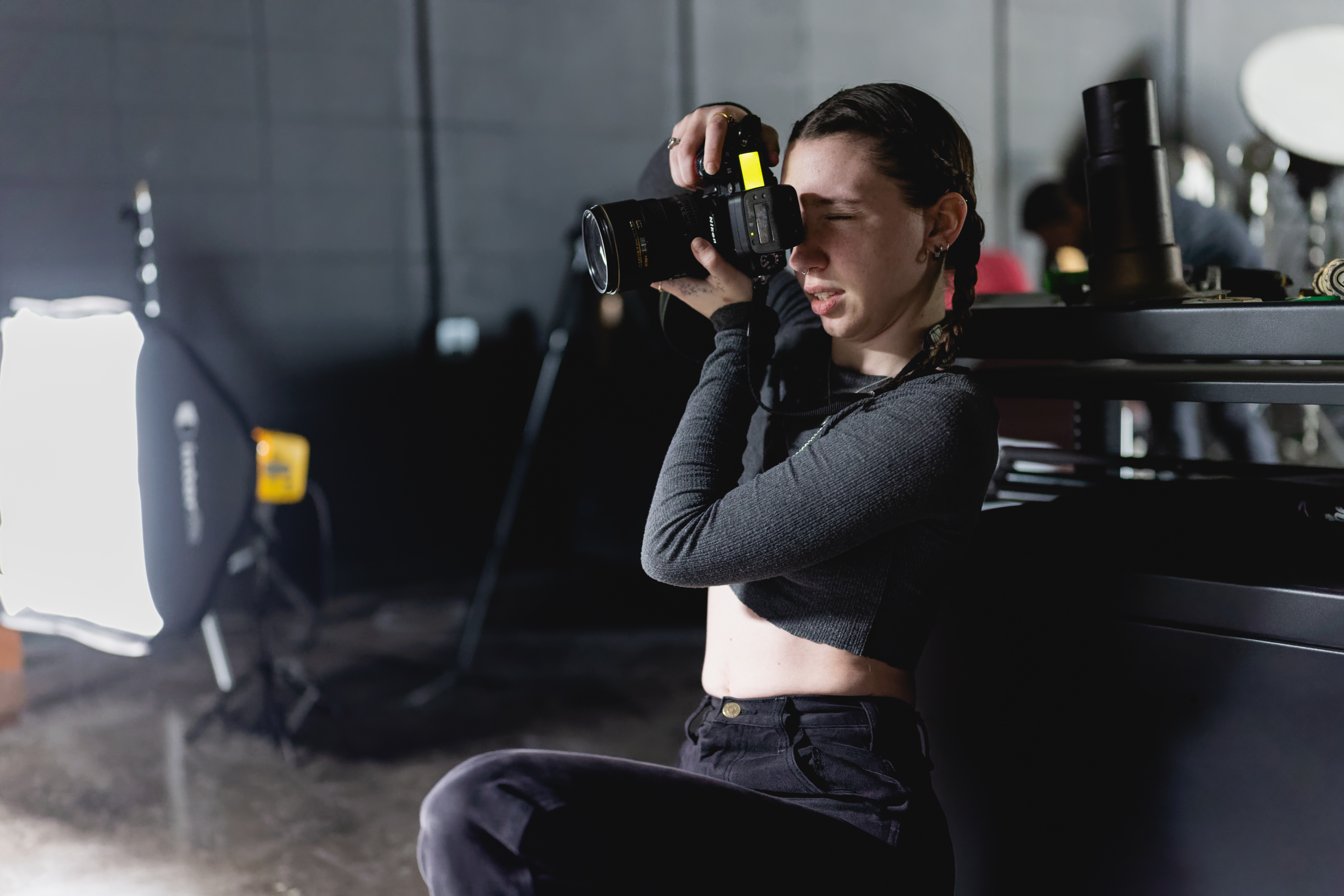 Photography student framing a shot with a DSLR camera in a studio