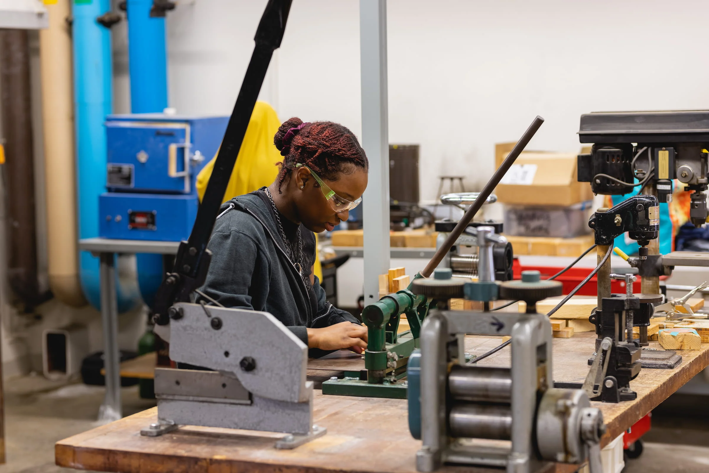Student operating a machine in a manufacturing workshop