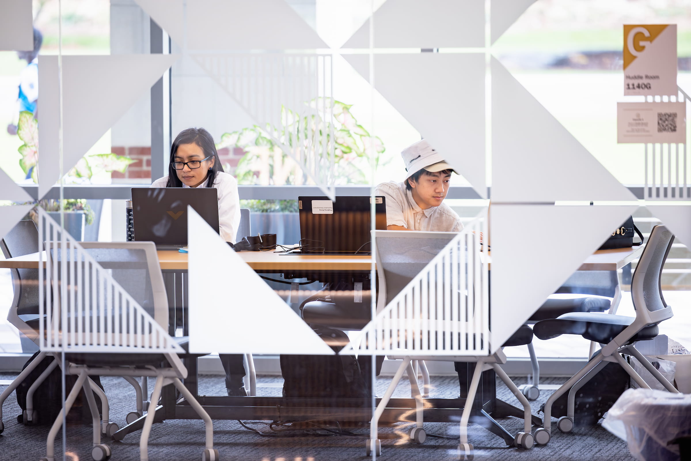 Students working in a glass-partitioned study space