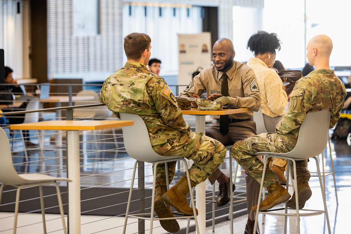 Two uniformed members of the military sitting with a Central Piedmont representative at a table in the student center