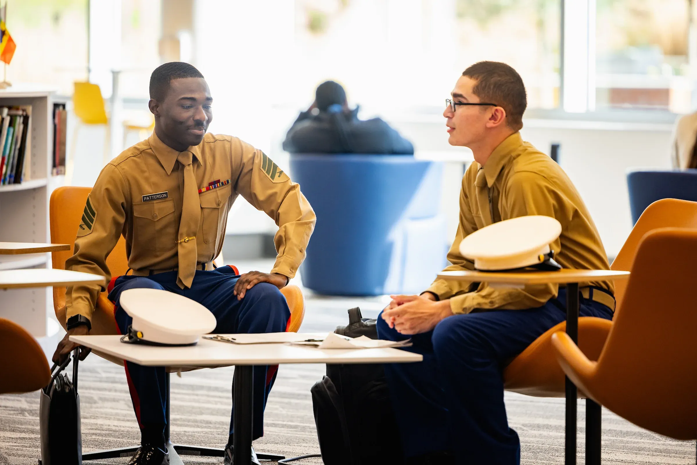 Two service members in uniform talking in a campus lounge