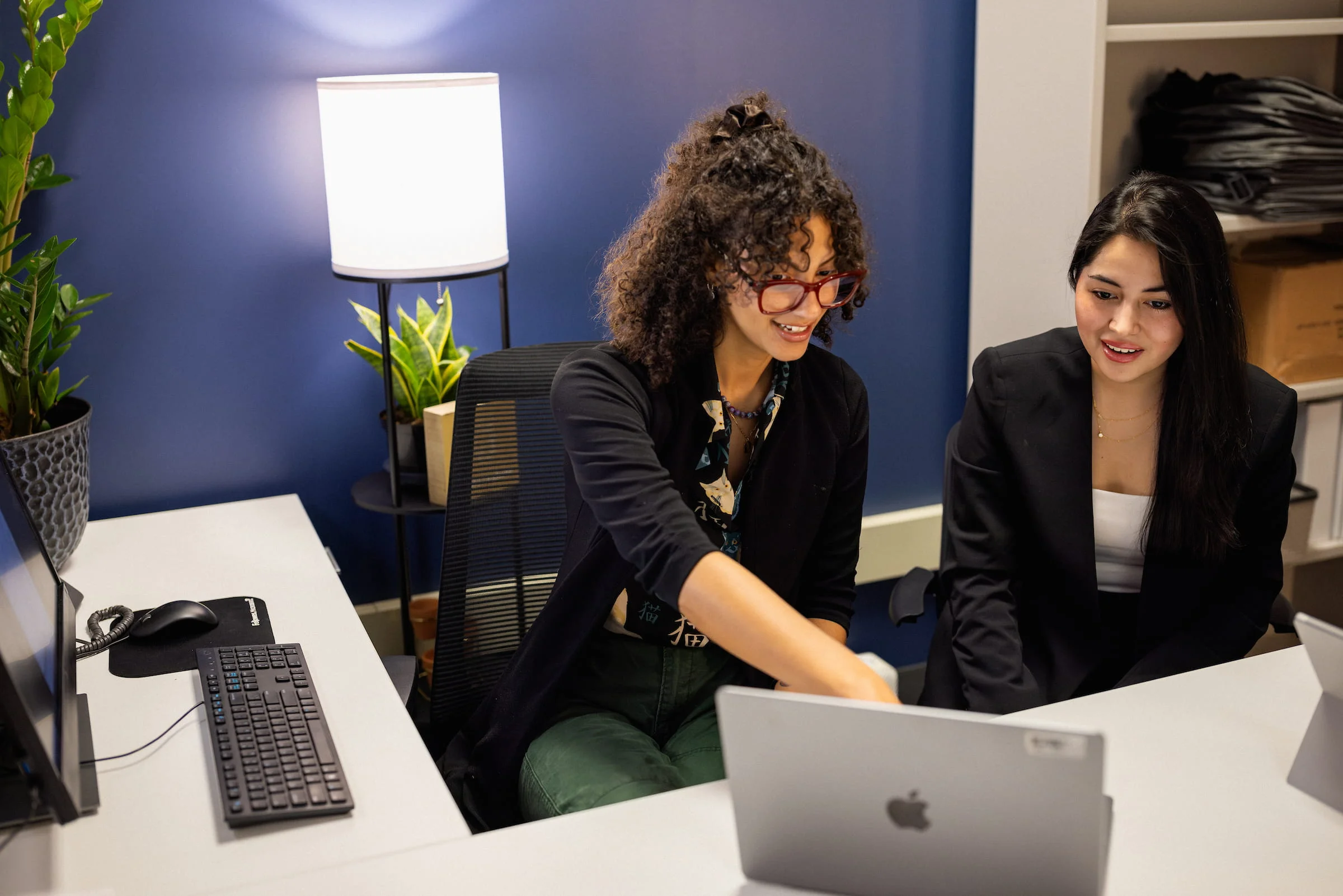 Two students working together at a laptop in an office