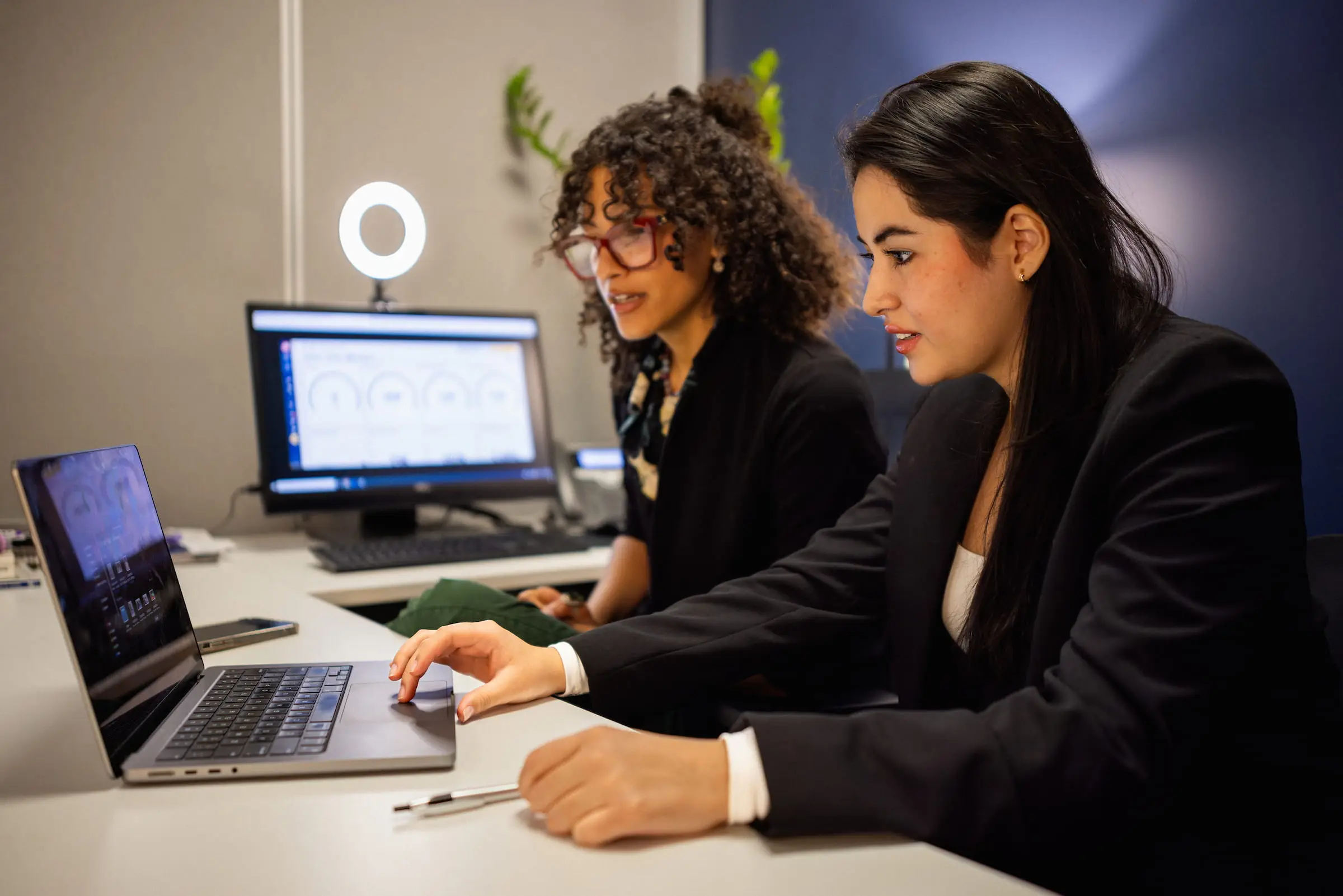 Two colleagues reviewing results on a laptop and monitor