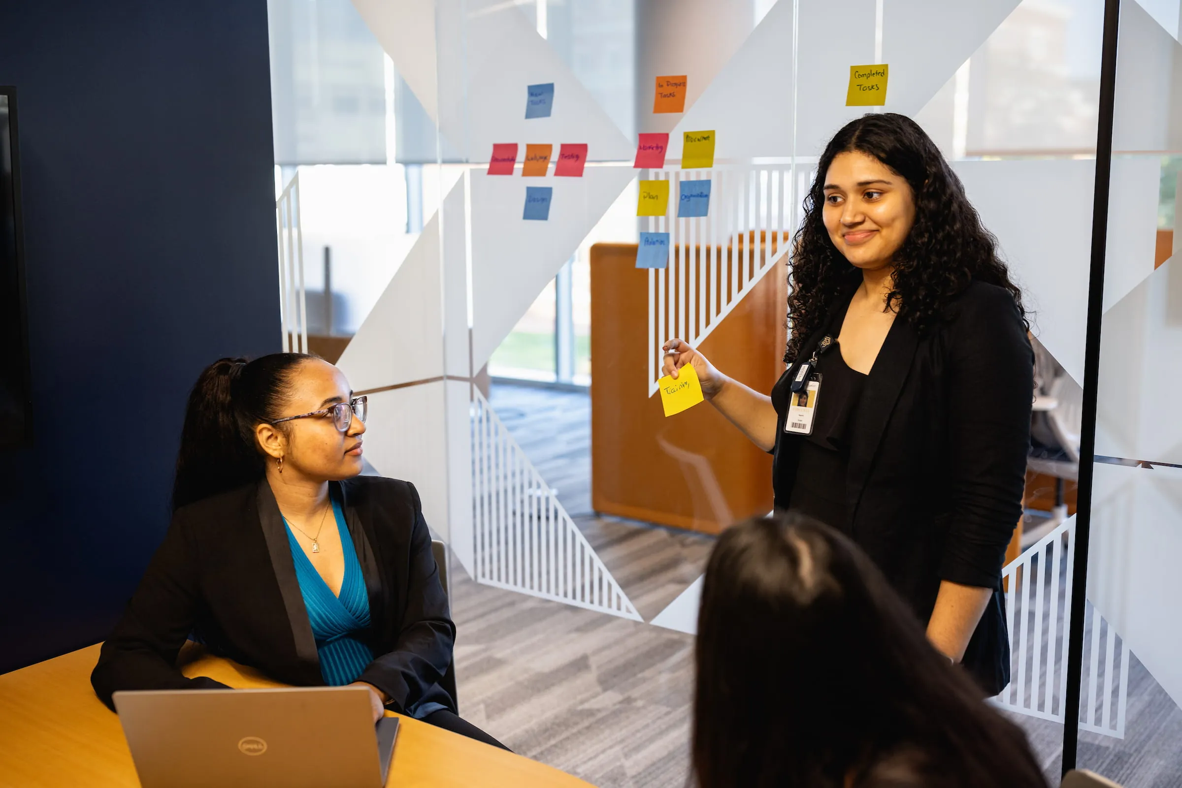 Presenter leading a workshop beside a board of sticky notes