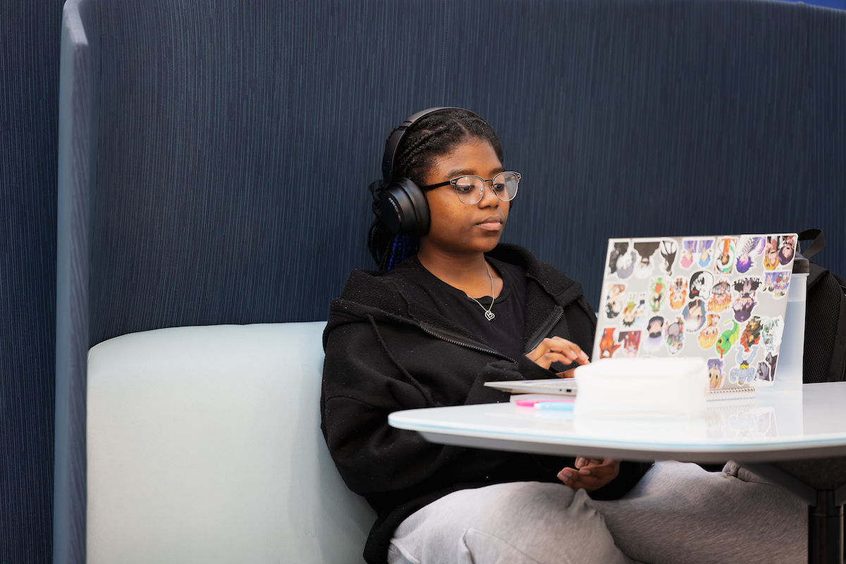 Student sitting at a desk with a laptop open and headphones on.