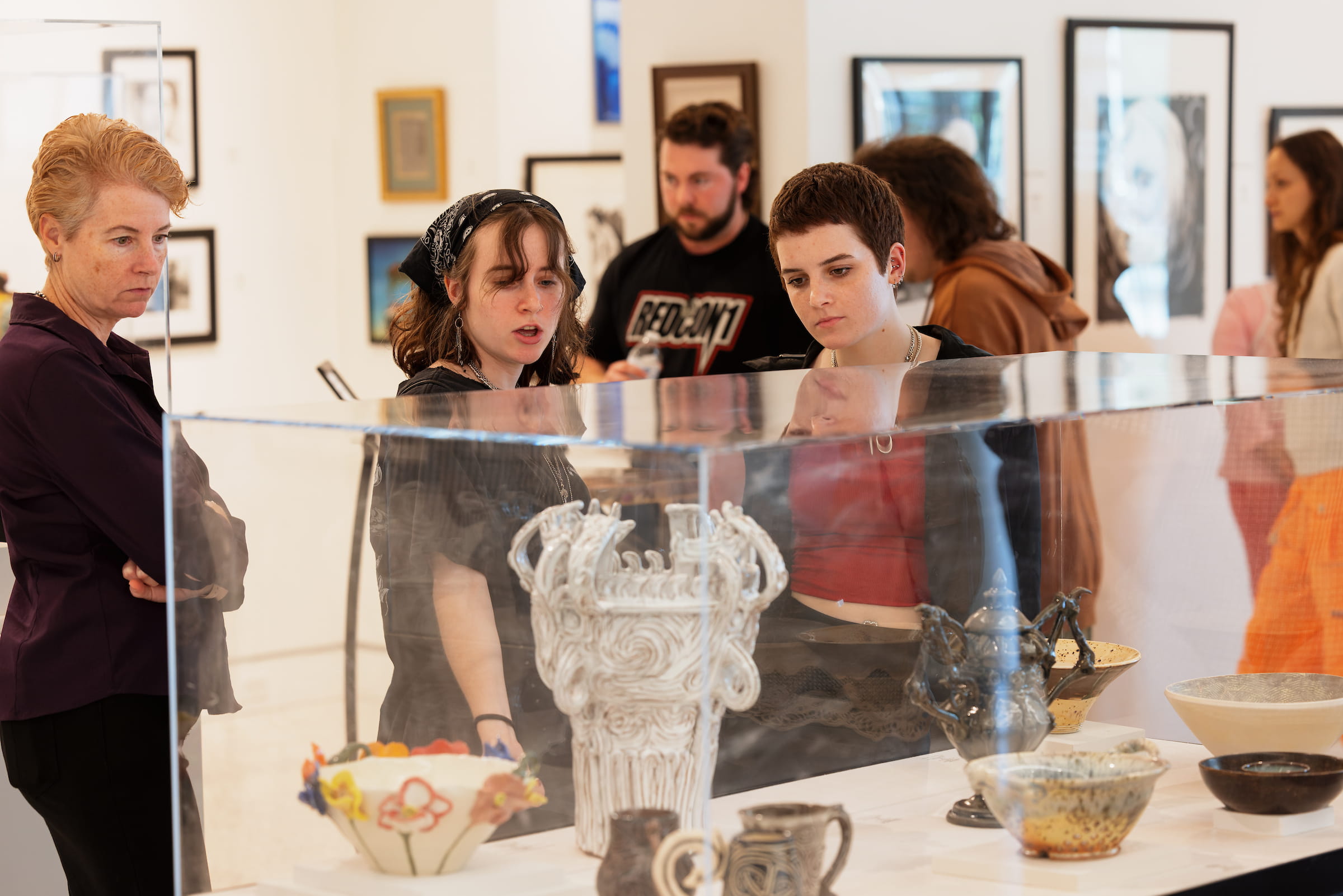 Visitors viewing glass artwork in a gallery display case