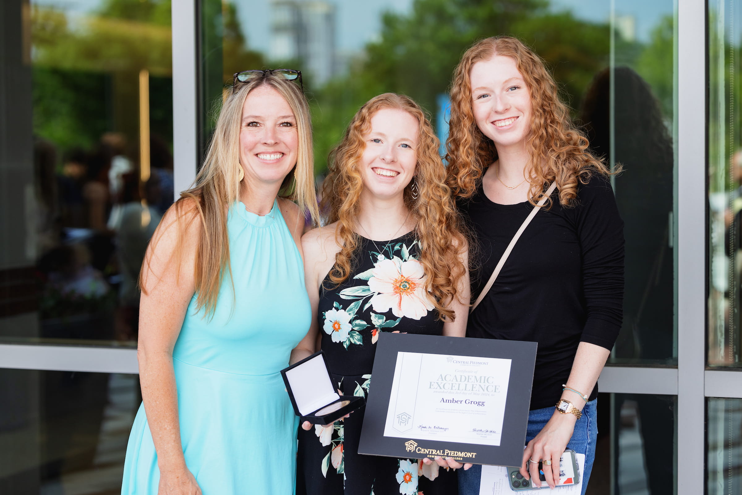 Three scholarship recipients holding a framed certificate