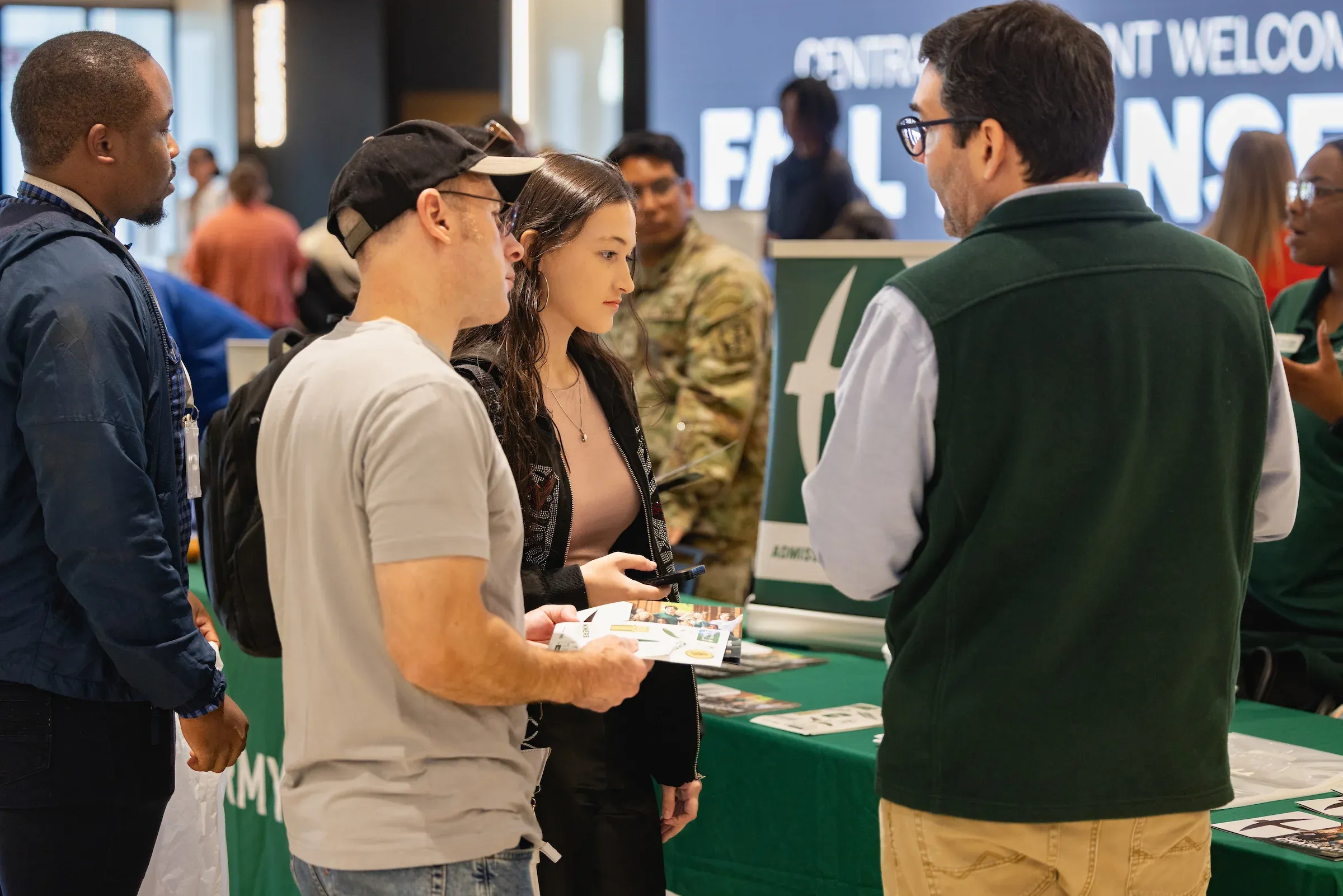 Students talking with staff at a welcome event table