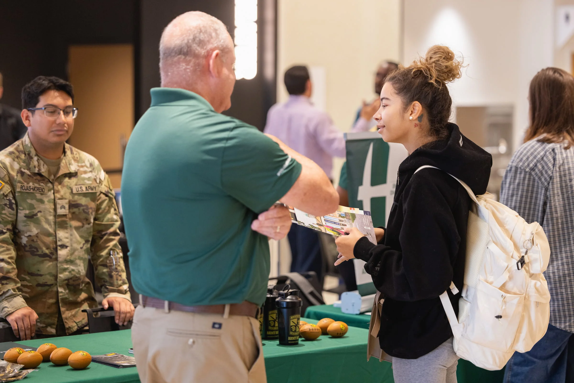 Staff member handing a leaflet to a student at a veterans services table