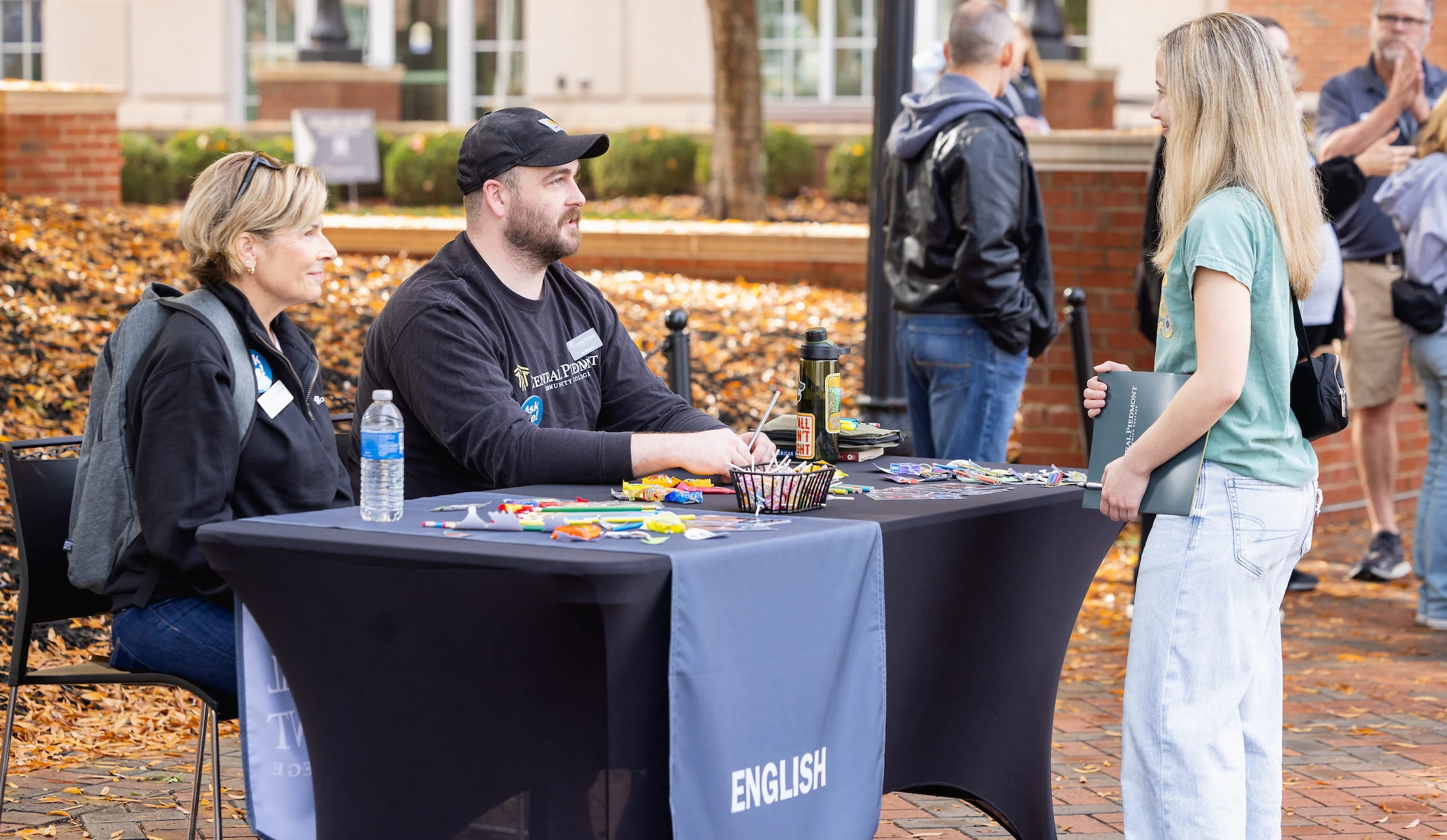 Staff talking with students at an outdoor English programme table