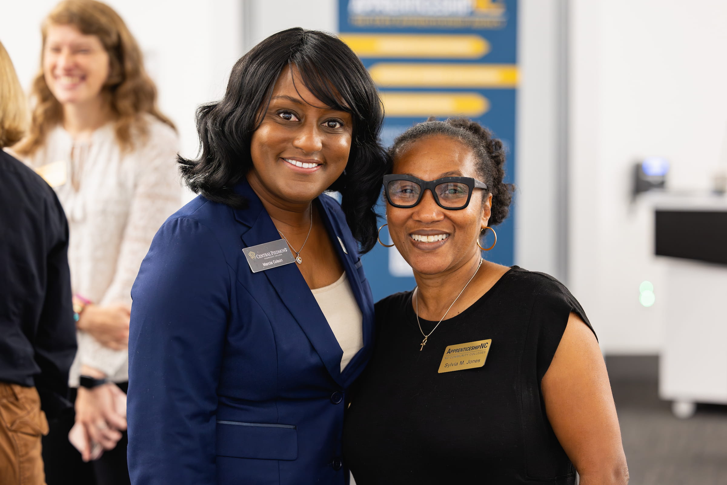 Central Piedmont student posing and smiling at camera alongside person sponsoring program.