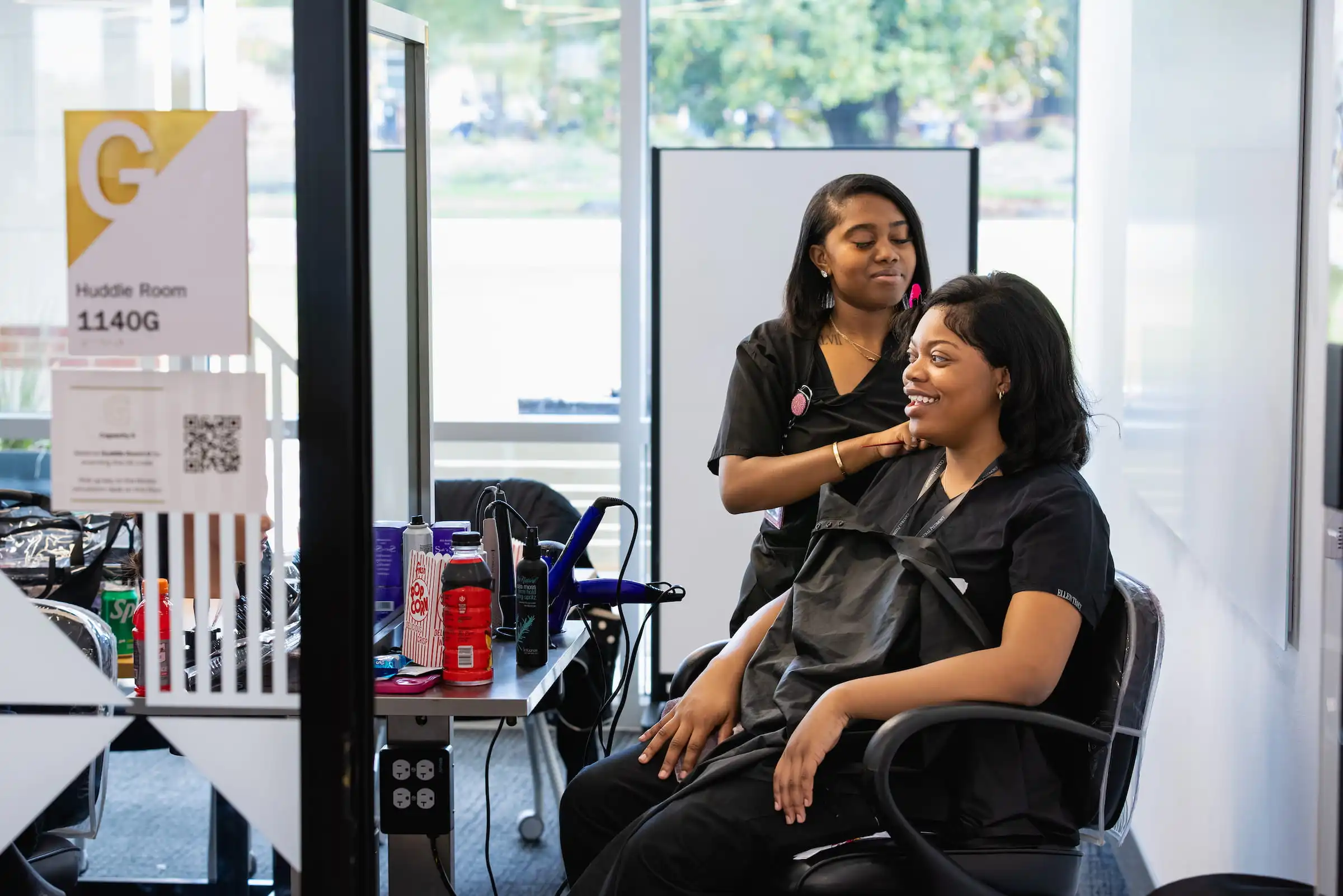 Cosmetology student talking with a client in a salon styling chair