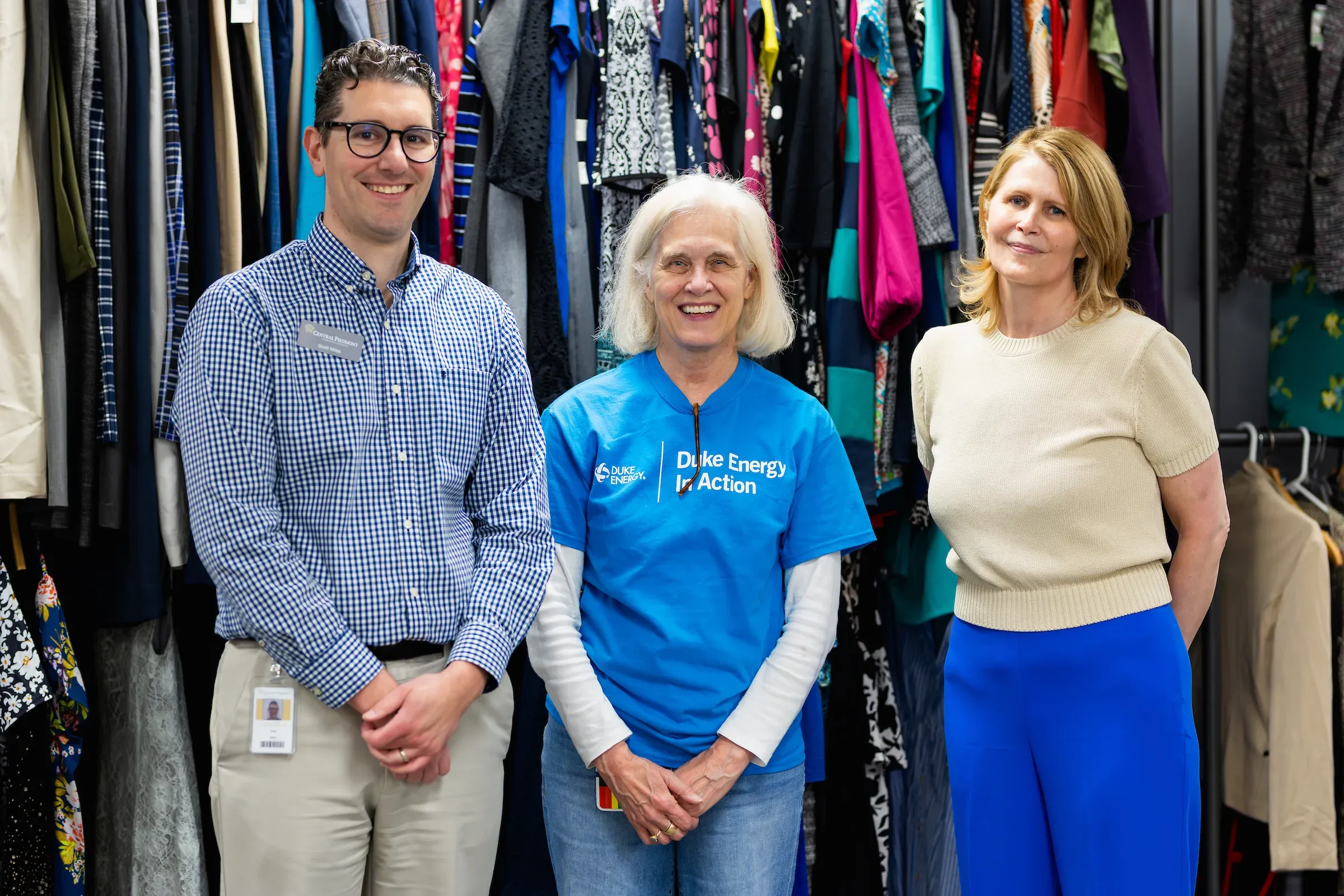 Three staff members in the professional clothing closet among garment racks