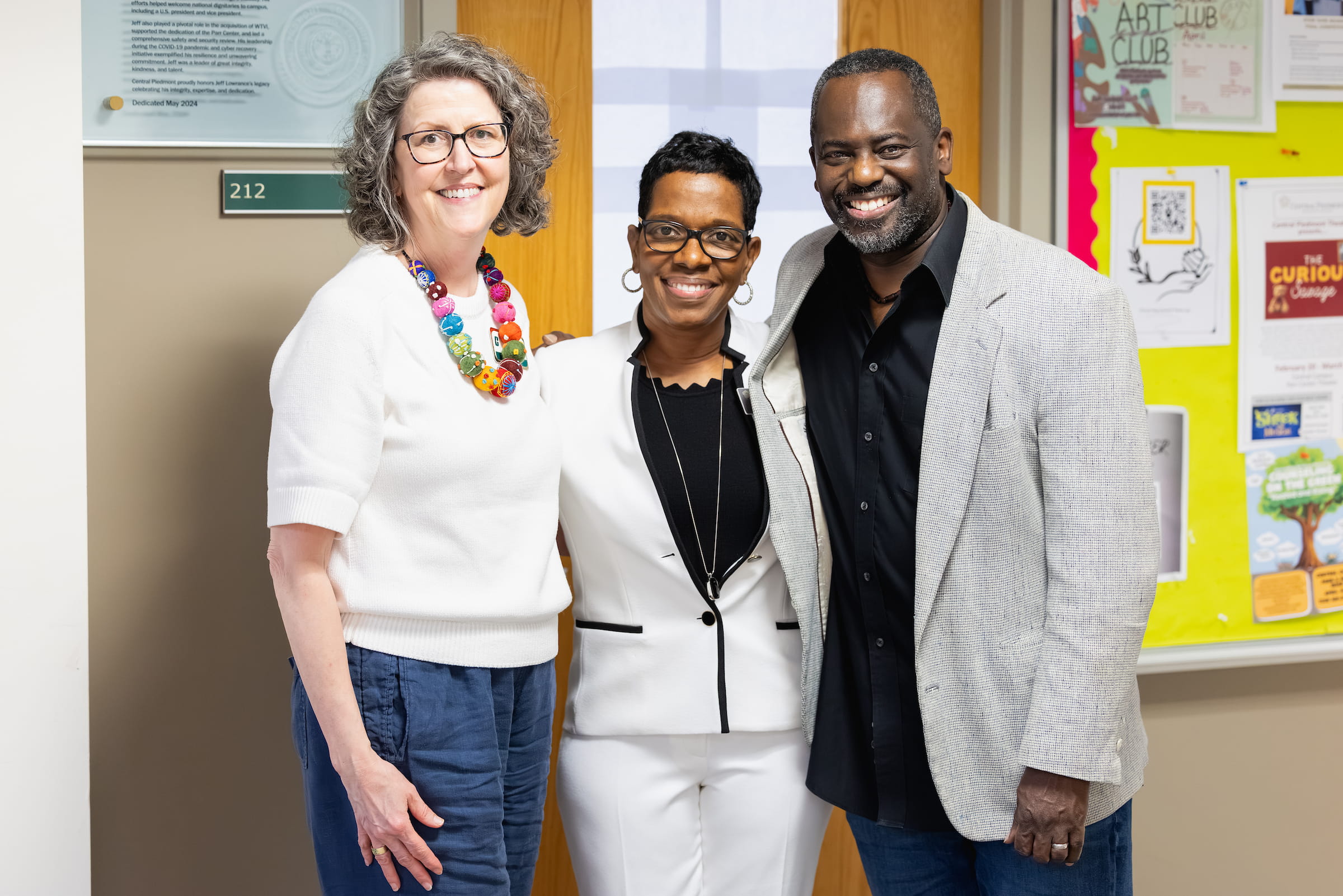 Three Central Piedmont staff members smiling together in an office