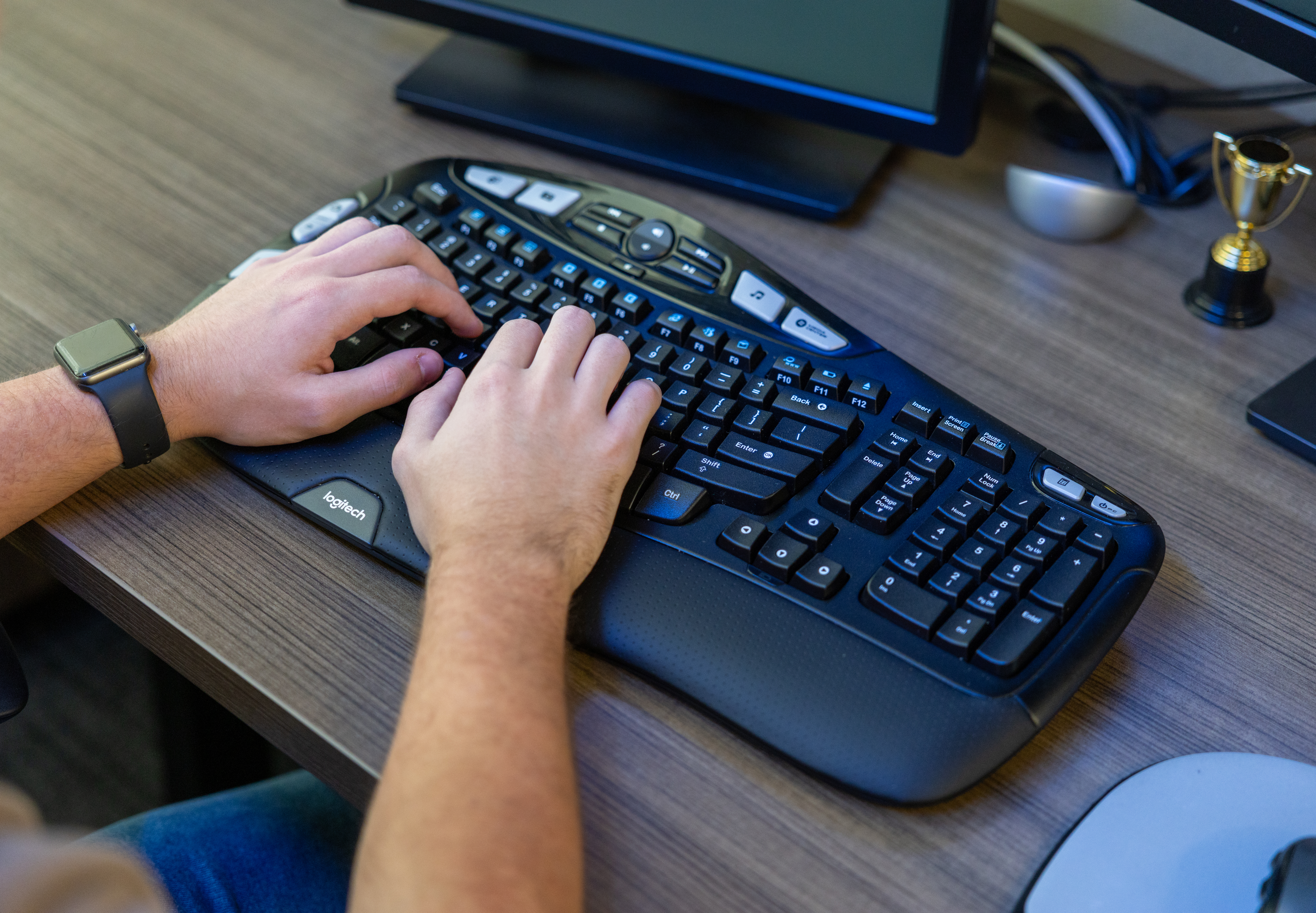 Close-up of hands typing on an ergonomic keyboard at a desk