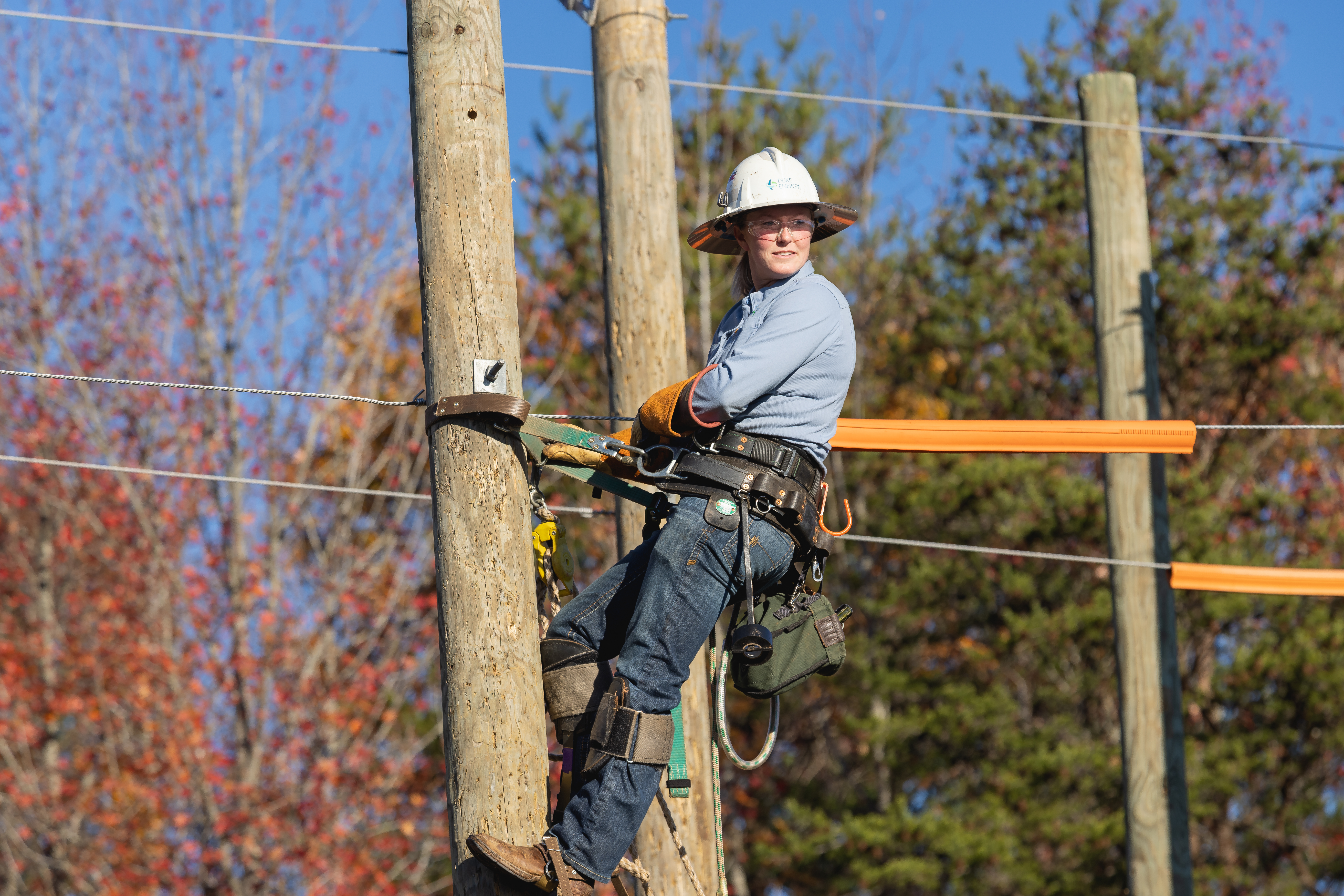 Lineworker student in a hard hat climbing a utility pole