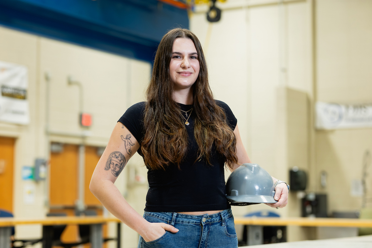 Student Deborah Riley standing in a classroom, holding a hard hat.