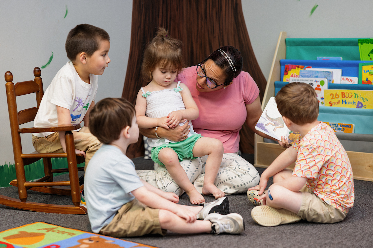 Central Piedmont student reading to four elementary-age children
