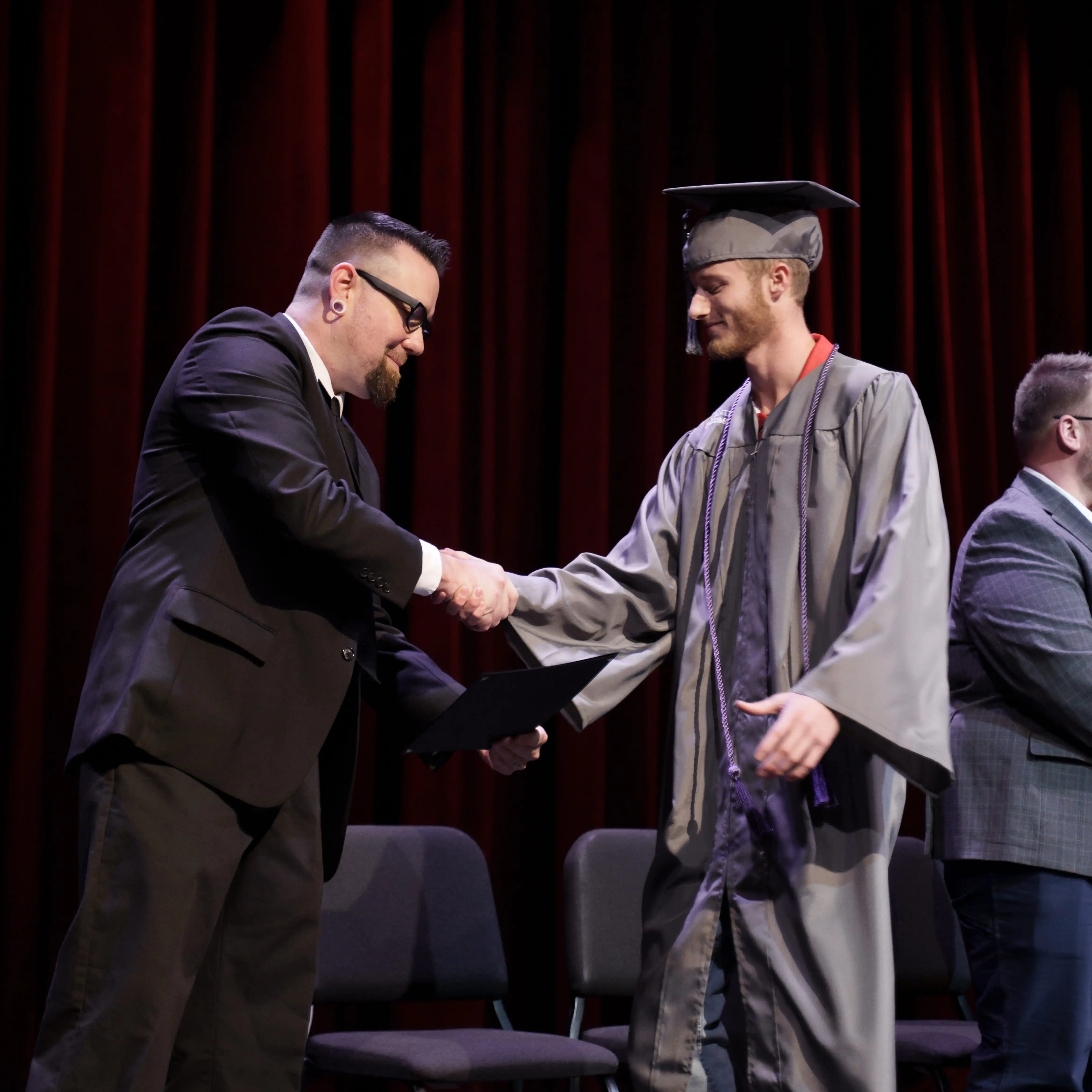 Graduate shaking hands with a college official on stage
