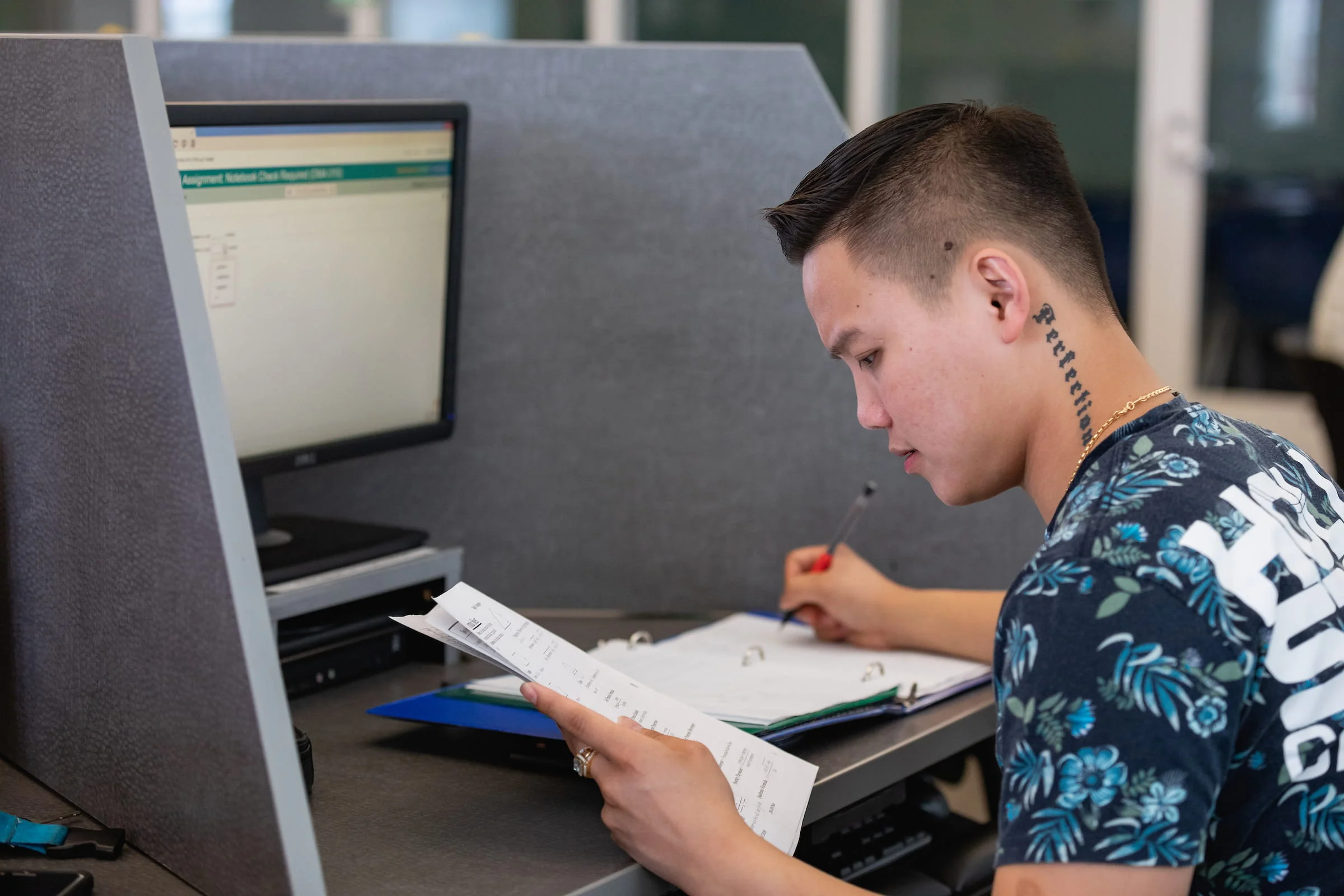 Student reading a booklet at a computer testing station